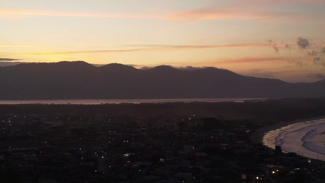 鸟瞰图的城市轮廓沿着海岸在夕阳背后的山视频素材