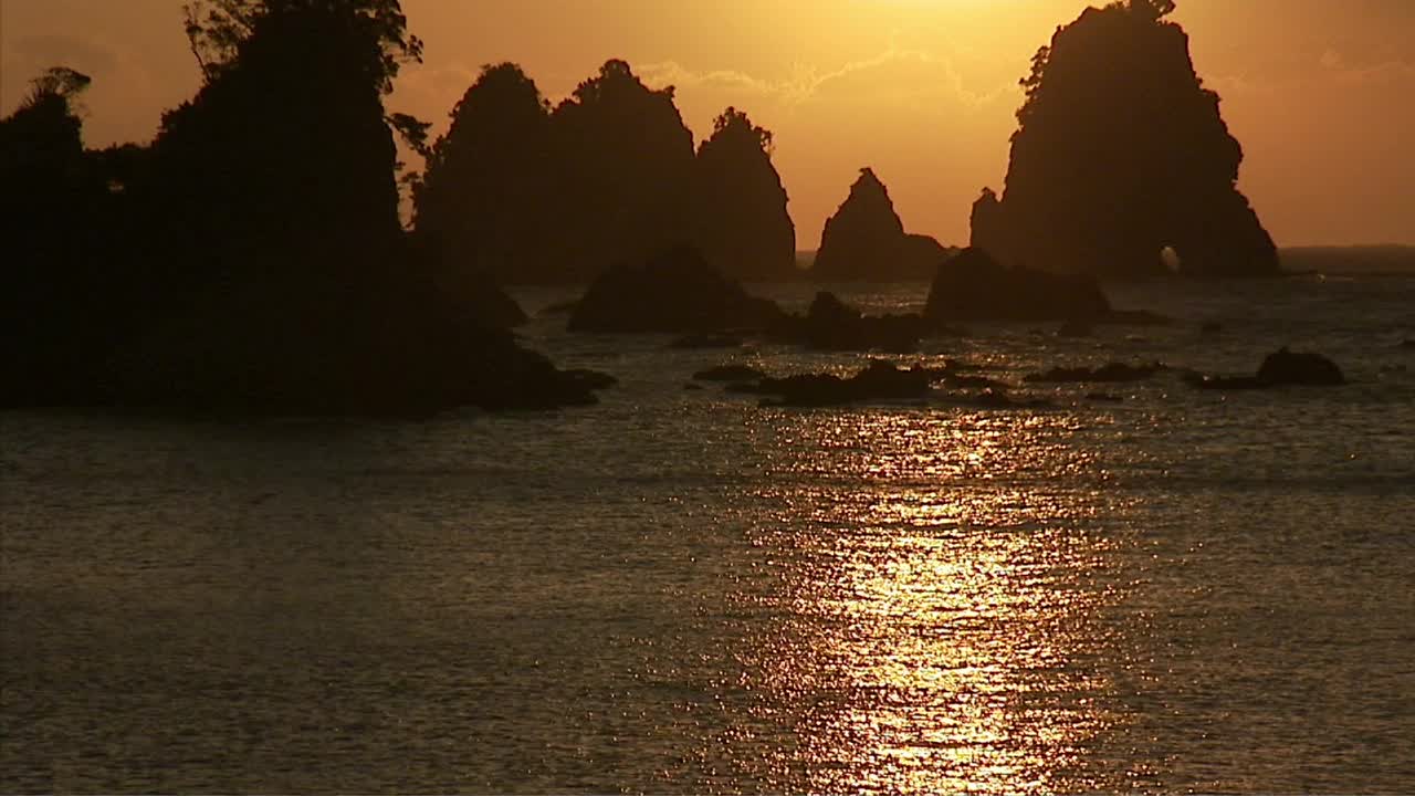 海洋岩层的剪影映衬着明亮的天空视频素材