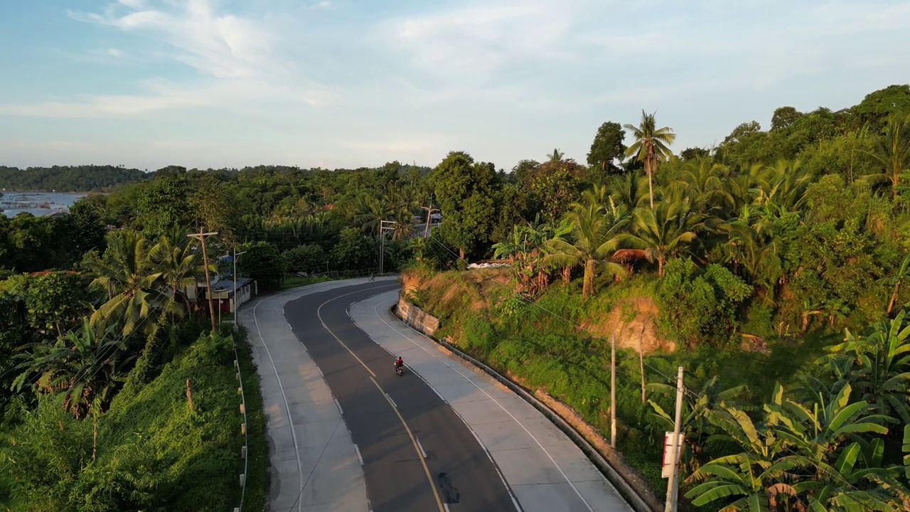 两车道高速公路环绕着棕榈树在夕阳的黄昏视频素材