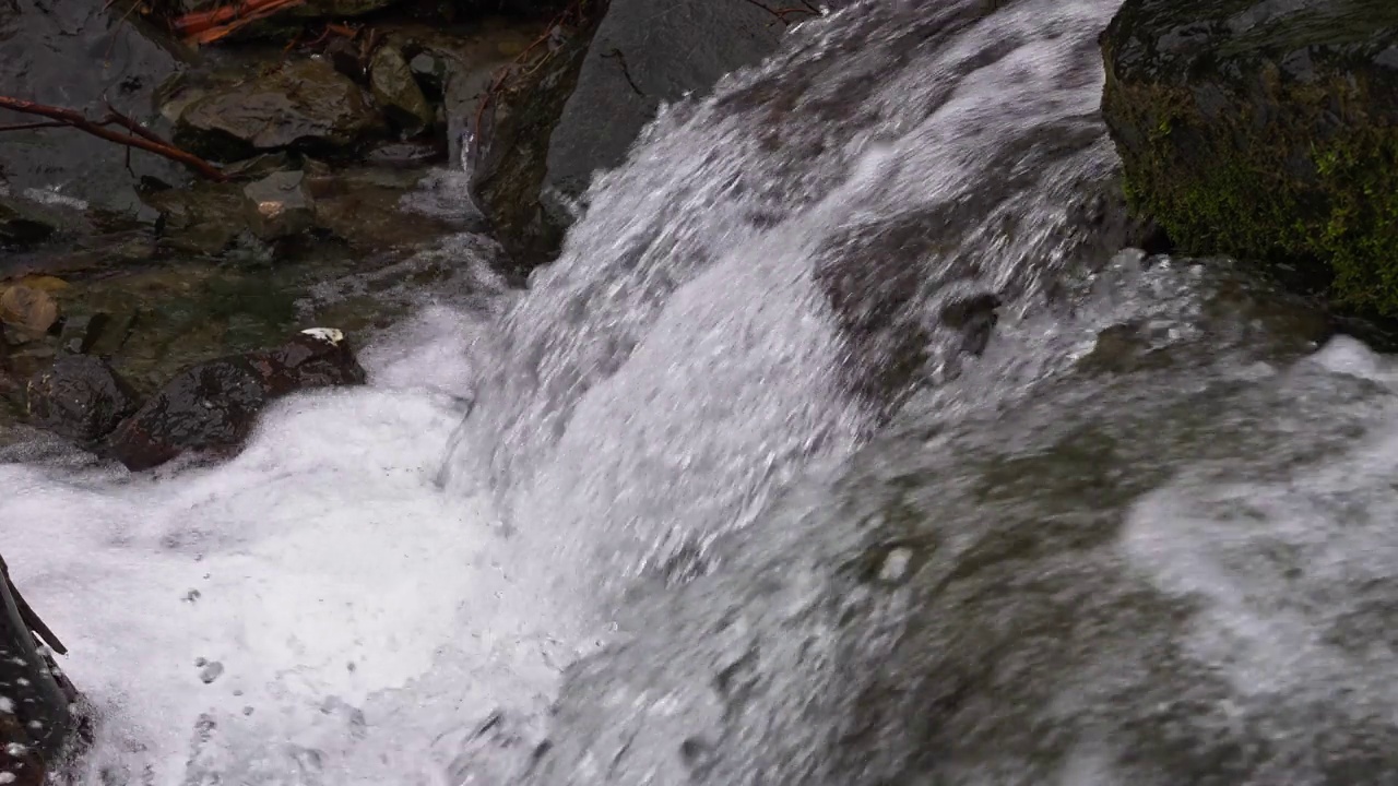 一股山涧的激流穿过石头。山间溪流中的纯水是由于雪的融化而形成的。视频素材