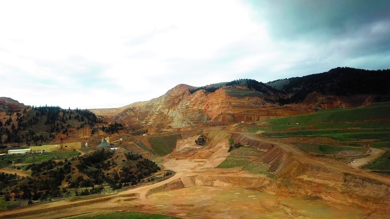 空中拍摄的建筑物在植物和树木附近的山，无人机飞行在景观对多云的天空-比林斯，蒙大拿州视频素材