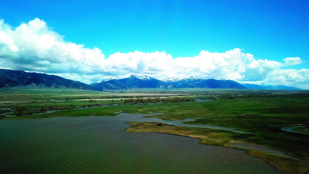 空中拍摄的河流附近的植物和山脉对天空，无人机在自然景观飞行向前-比林斯，蒙大拿州视频素材