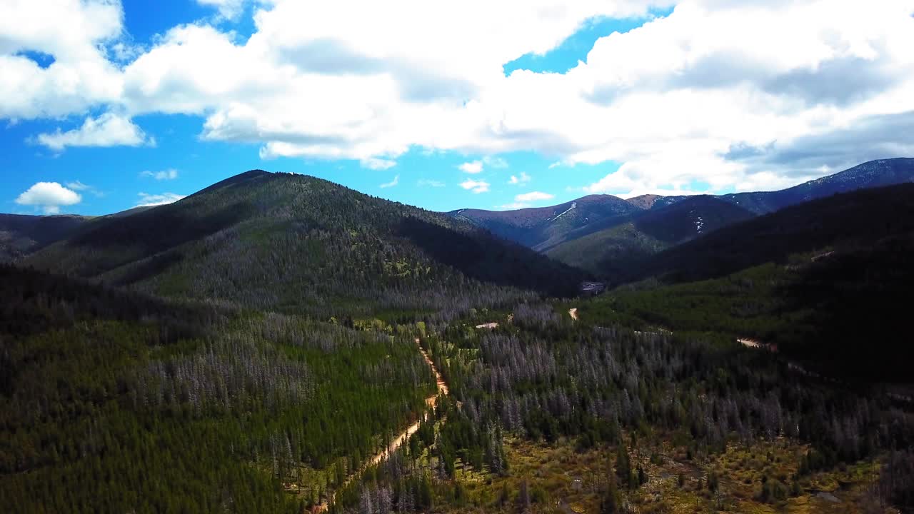 空中平移拍摄的道路在山附近的树木对天空，无人机飞越自然绿色景观-比林斯，蒙大拿州视频素材