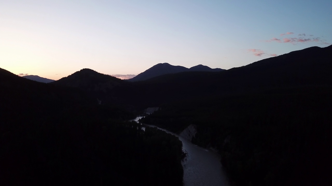 空中平移拍摄的河流剪影树木附近的山，无人机飞越自然景观对天空在黄昏-利比，蒙大拿州视频素材