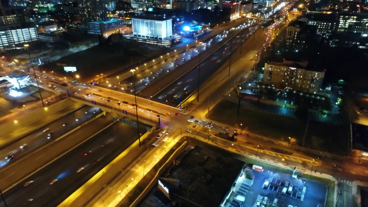 空中倾斜拍摄的车辆在高速公路附近的照明建筑物，无人机在城市上空对着天空在夜间飞行-亚特兰大，乔治亚州视频素材