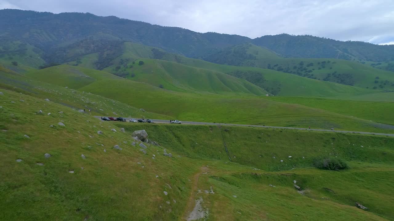 空中:无人机向前飞向车辆和人在路边的山脉-贝克斯菲尔德，加州视频素材