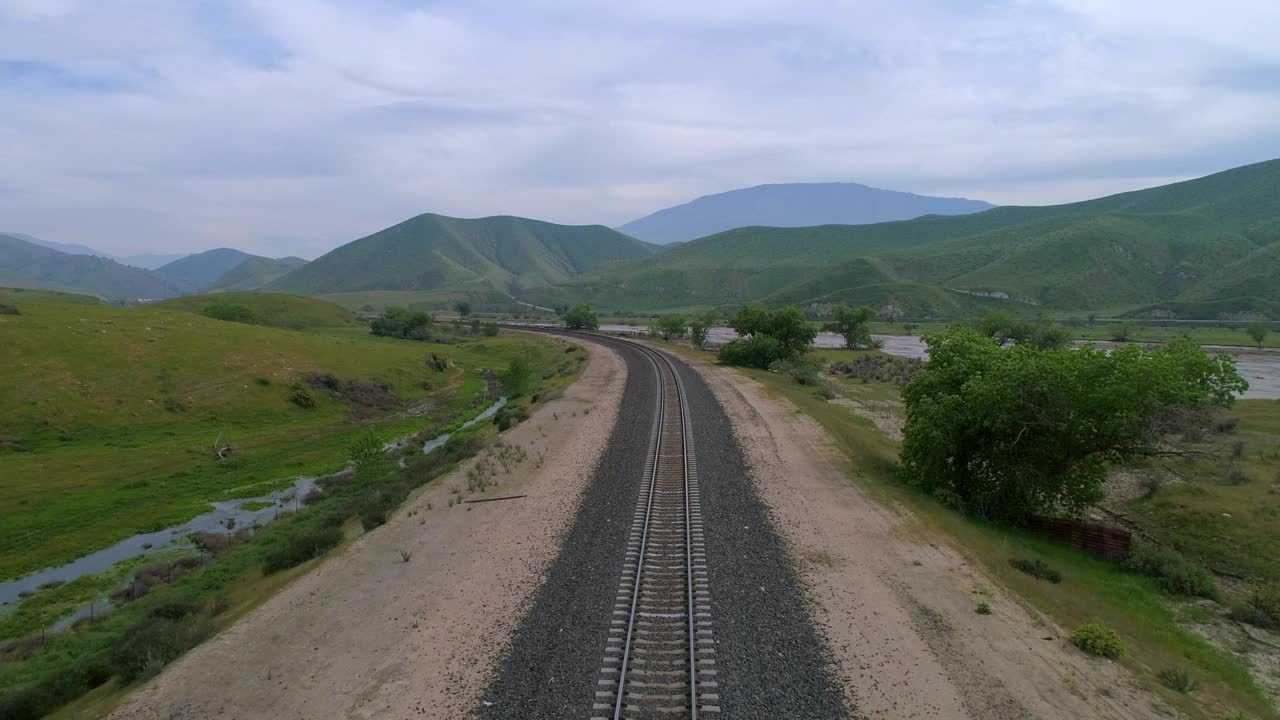 航拍的铁路桥上的河流附近的道路，无人机在绿色景观逆空上升，贝克斯菲尔德，加州视频素材