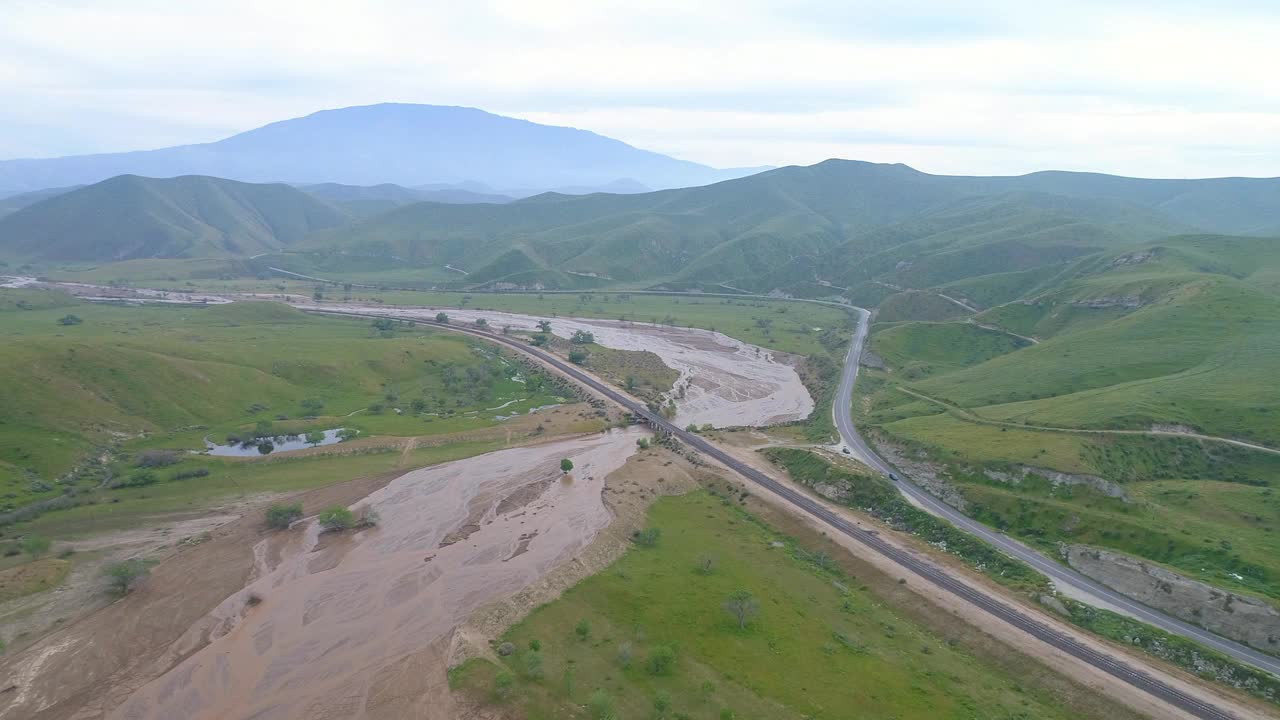 航拍的铁路桥上的河流附近的道路，无人机下降在景观在多云的天空，贝克斯菲尔德，加州视频素材