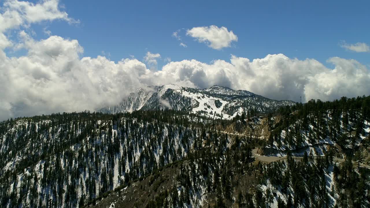 空中拍摄的车辆在道路附近的树木在山脉，无人机在冬季景观逆空飞行-大熊湖，加州视频素材