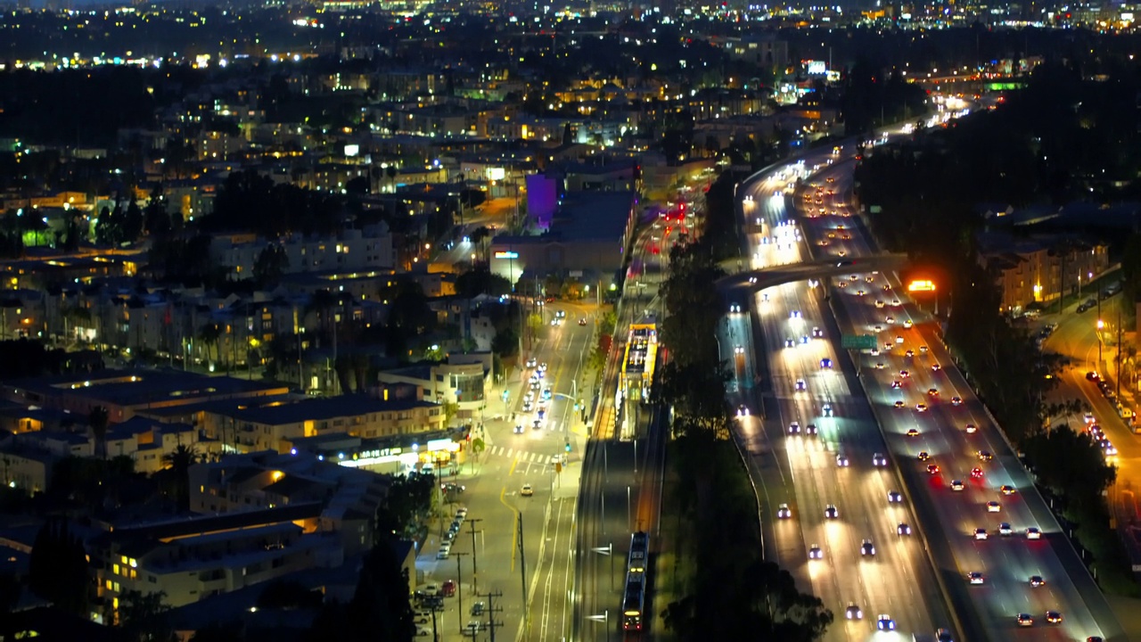 空中倾斜拍摄照亮的铁路轨道和高速公路在城市的天空在黄昏-卡尔弗城，加州视频素材