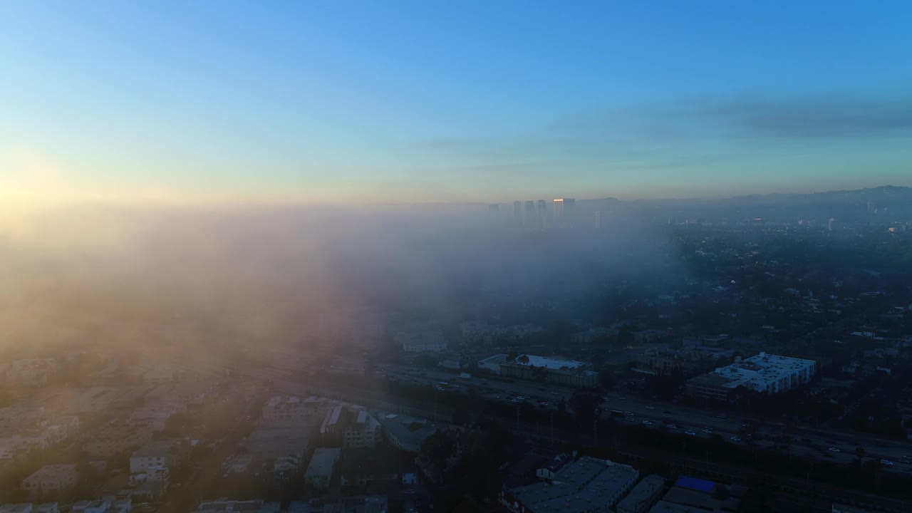 空中向后拍摄的车辆和建筑物在城市对天空在日出-卡尔弗城，加州视频素材