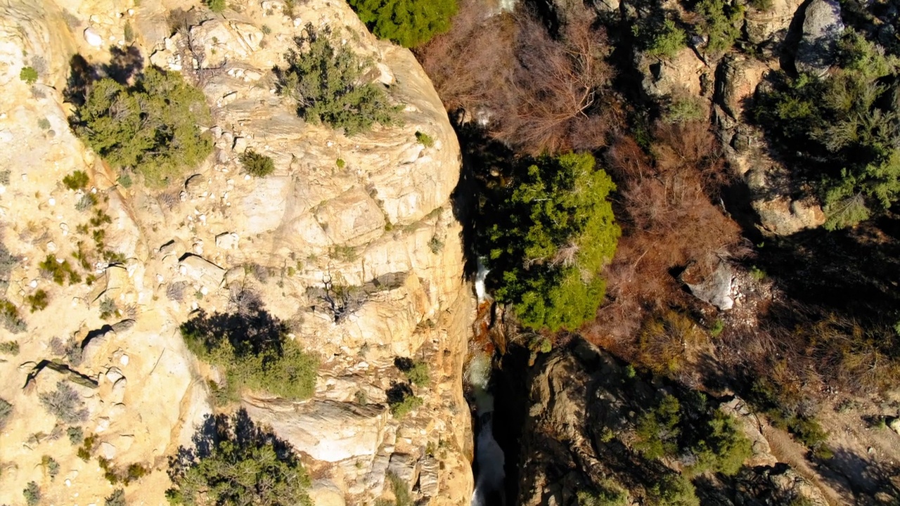 空中顶景的田园诗般的瀑布在岩层中的森林，无人机飞行向前景观在阳光明媚的日子-毕晓普，加州视频素材