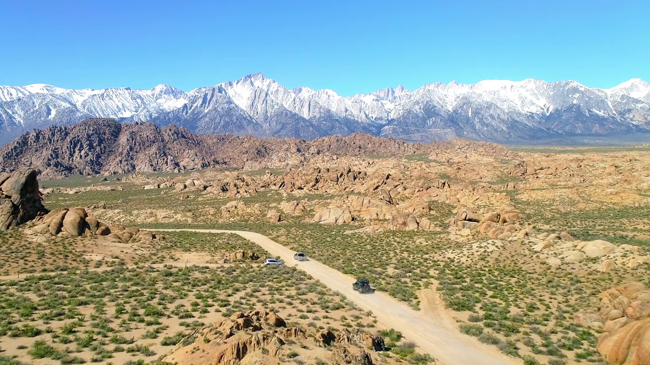 航拍的车辆移动的土路通往山，无人机飞越景观对蓝天-主教，加州视频素材