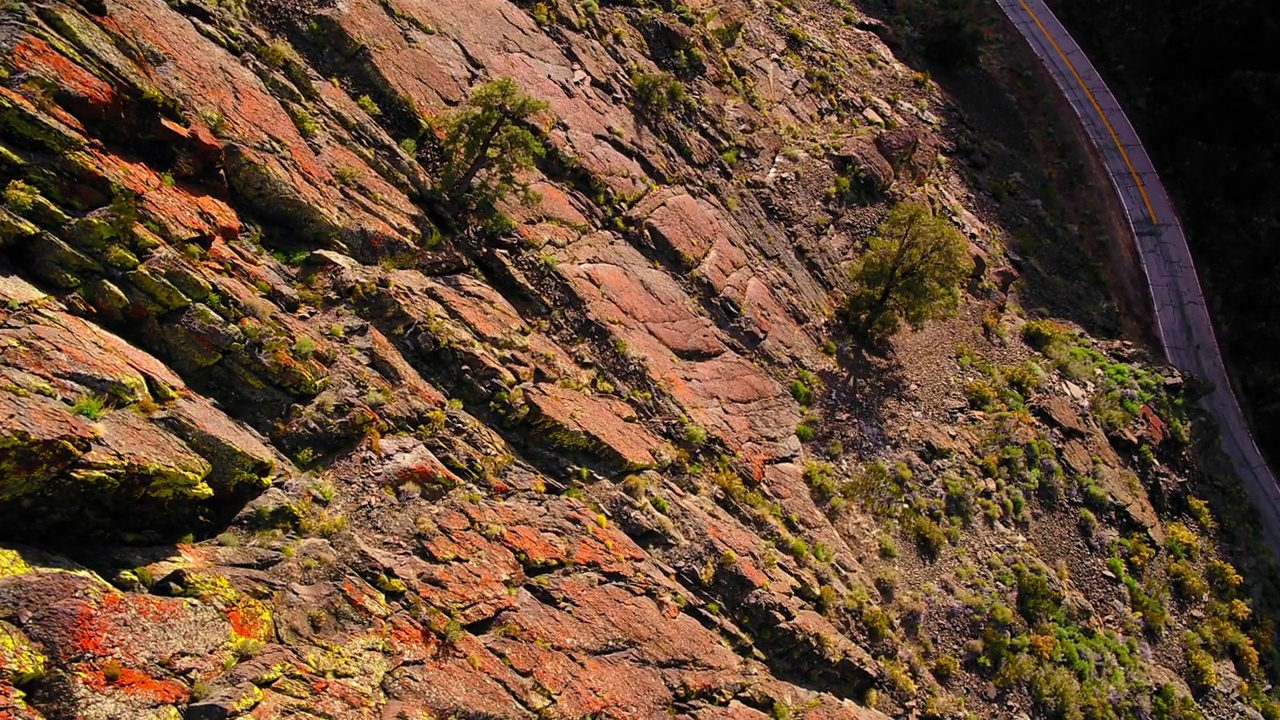 在阳光明媚的日子里，空空如也的道路在山谷中的群山中航拍-猛犸湖，加利福尼亚视频素材