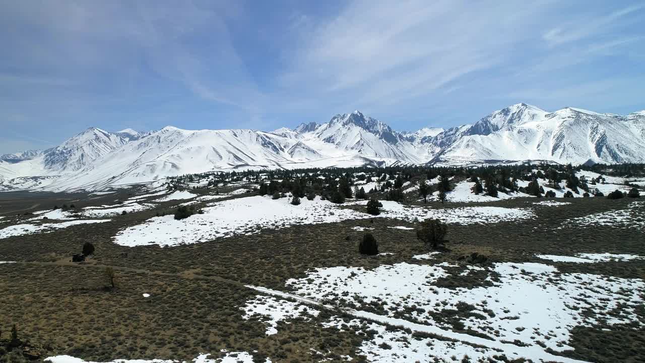 空中平移拍摄的雪与树木和植物附近的山，无人机降落在景观对天空-猛犸湖，加利福尼亚视频素材