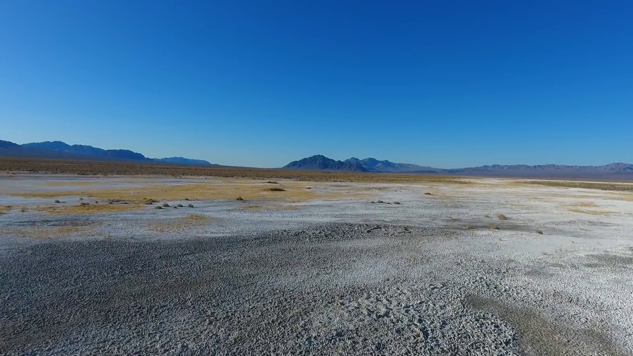 飞越令人惊叹的白色沙漠景观，飞向山脉视频素材