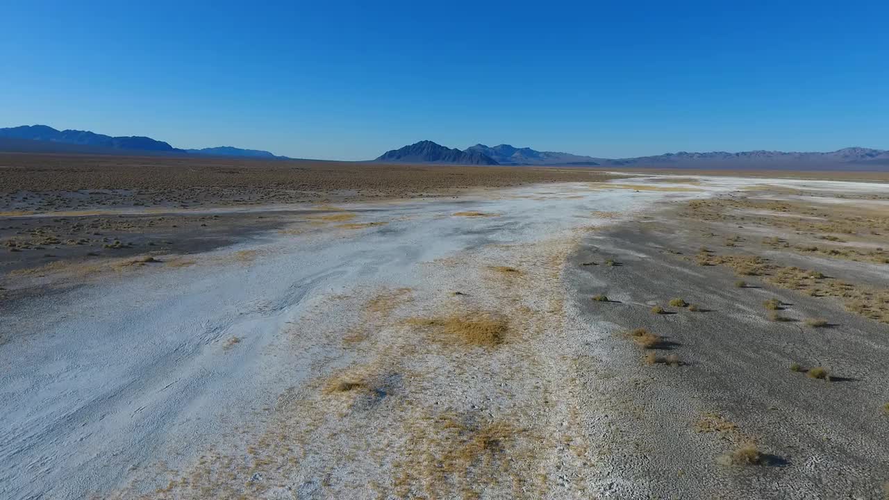 沿着白色和黑色的沙漠和遥远的死亡谷山脉飞行视频素材