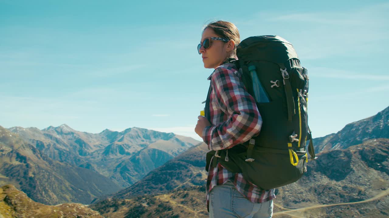 女游客背着徒步背包站在山顶度假旅行视频素材