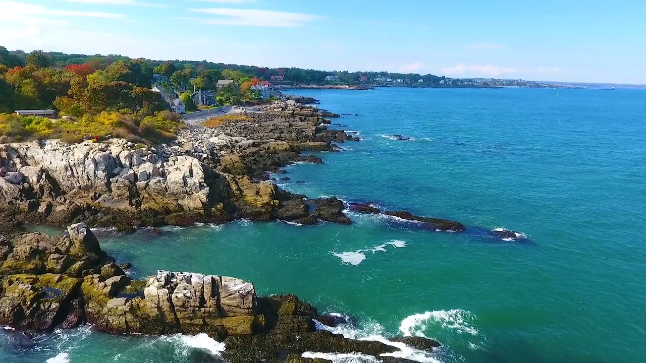 海浪冲击着缅因州海岸上的岩石，背景是房屋视频素材