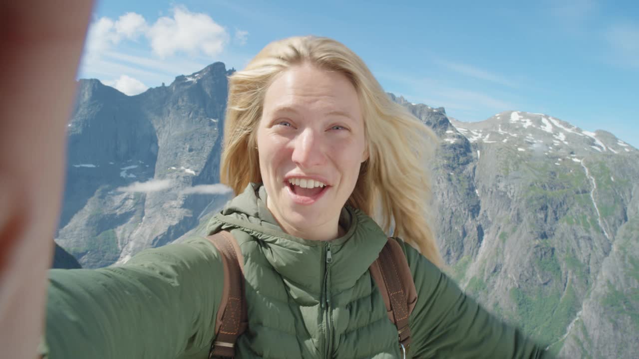 美丽的女人在户外用智能手机视频聊天，与朋友分享旅行冒险，女孩为社交媒体拍摄自拍视频照片，享受挪威Romsdalen山谷的假期视频素材