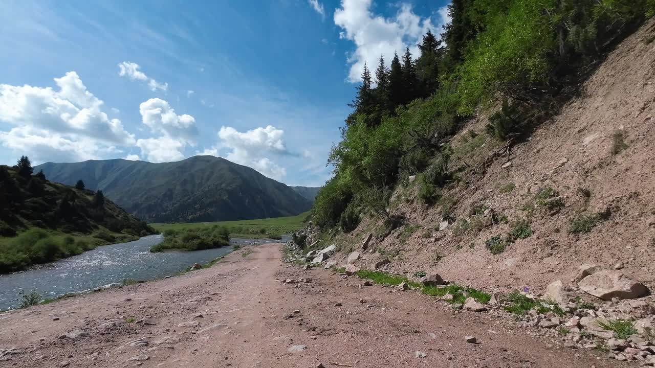 沿着山河和高大的森林岩石行驶在岩石山路上。汽车的观点视频素材