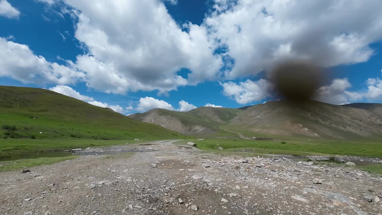 行驶在岩石路上，穿过绿色的山谷，有很多牧场(jailoo)。汽车的观点视频下载