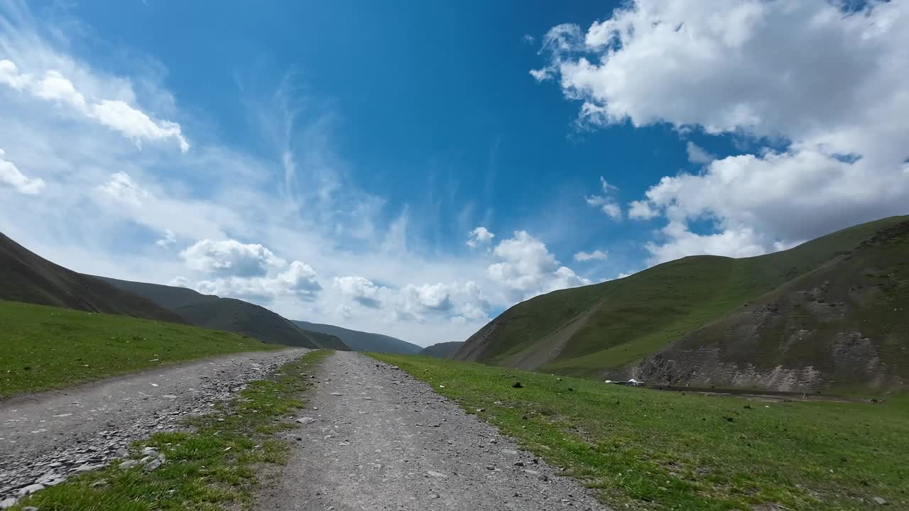 行驶在岩石路上，穿过绿色的山谷，有很多牧场(jailoo)。汽车的观点视频素材