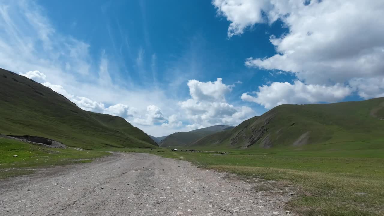 行驶在岩石路上，穿过绿色的山谷，有很多牧场(jailoo)。汽车的观点视频素材