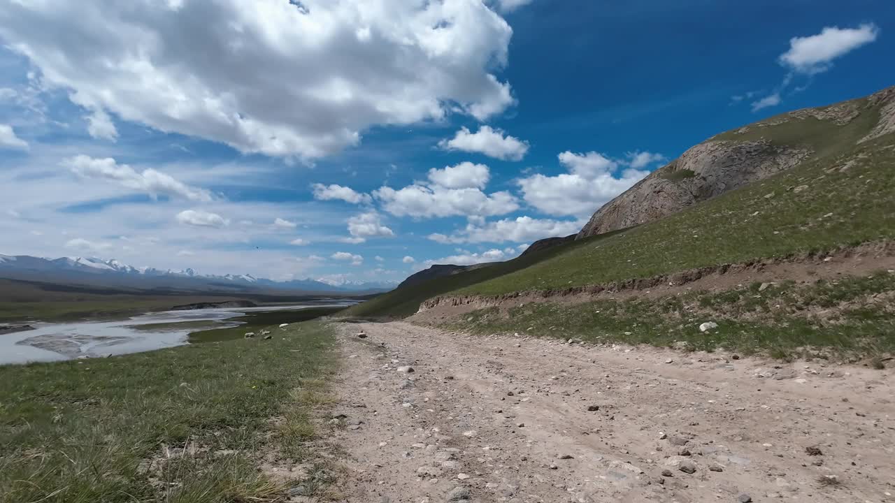 沿着山河行驶在土石路上。汽车的观点视频素材