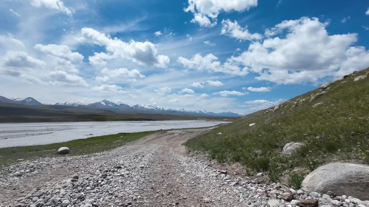 沿着山河行驶在土石路上。汽车的观点视频素材