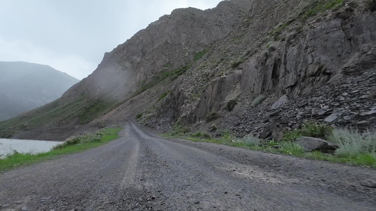 沿着山河行驶在土石路上。汽车的观点视频素材