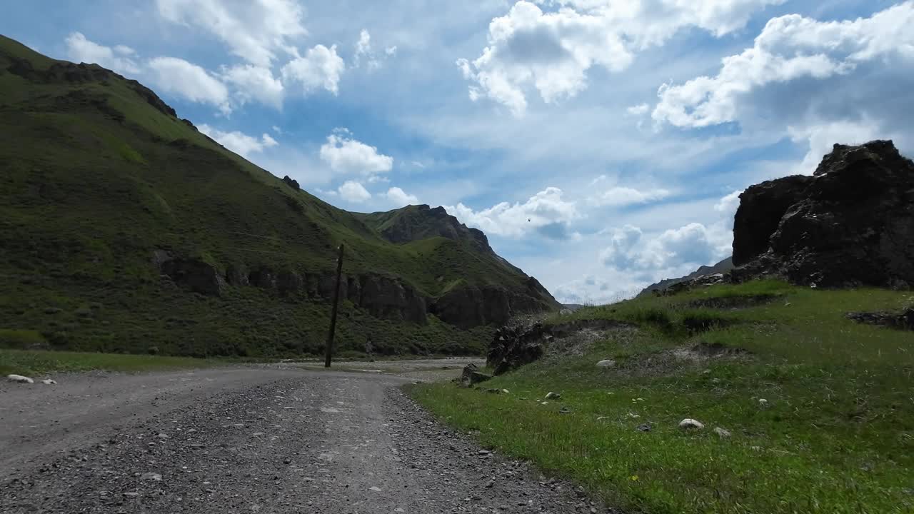 沿着山河行驶在土石路上。汽车的观点视频素材