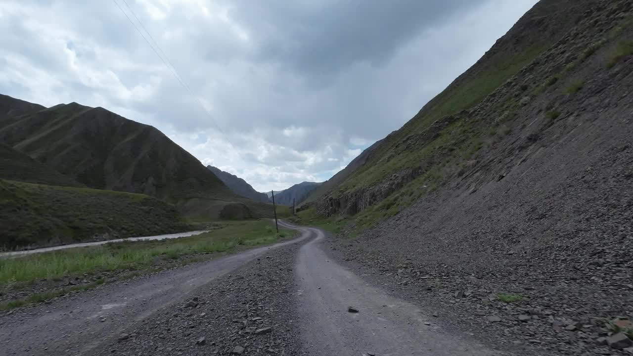 沿着山河行驶在土石路上。汽车的观点视频素材