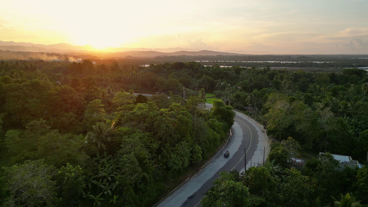 夕阳下的热带风景中有车辆的道路视频素材