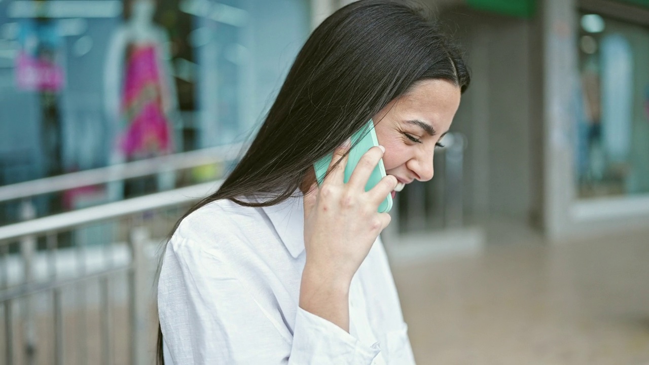 年轻漂亮的西班牙女人在街上用智能手机聊天视频素材