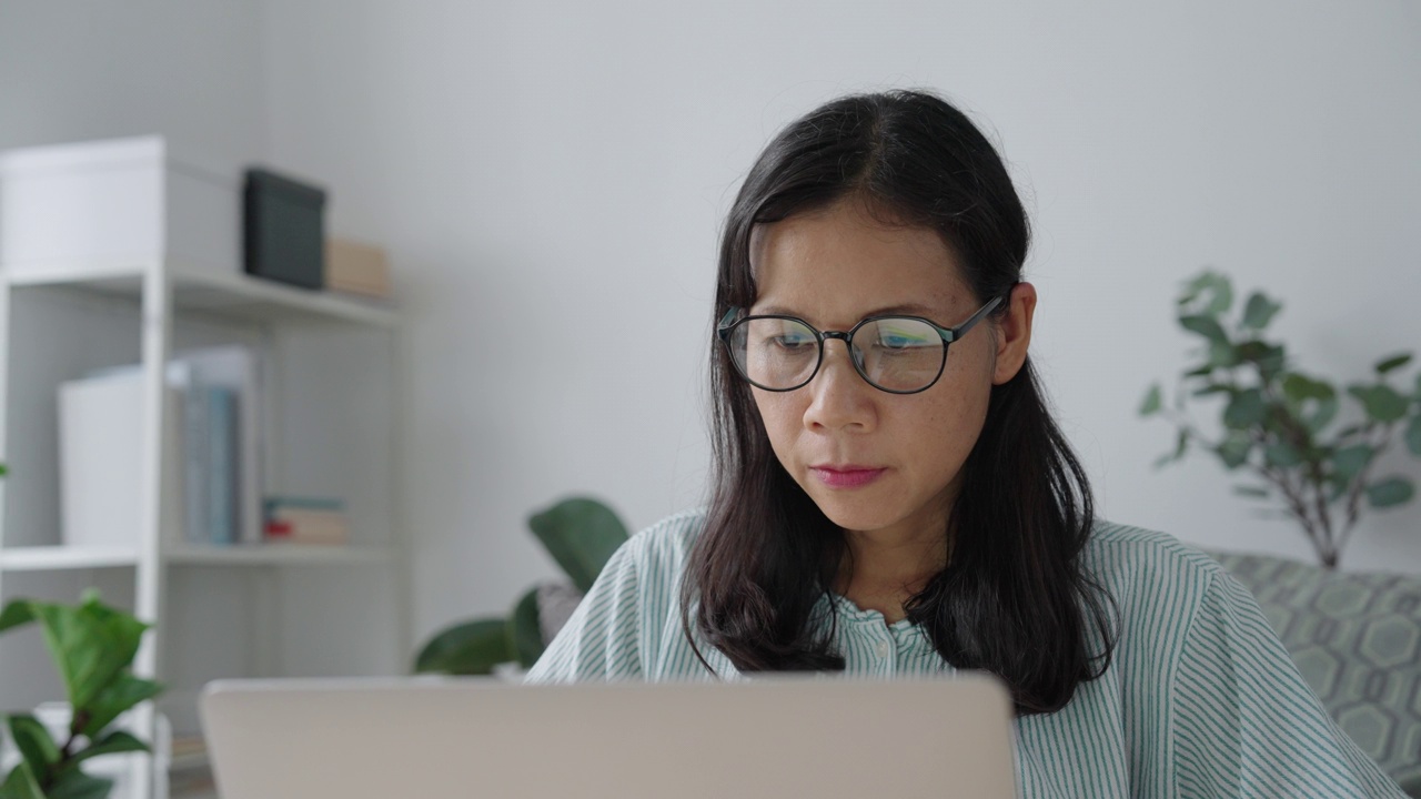 肖像。亚洲女人用笔记本电脑，在家打公司报告视频素材