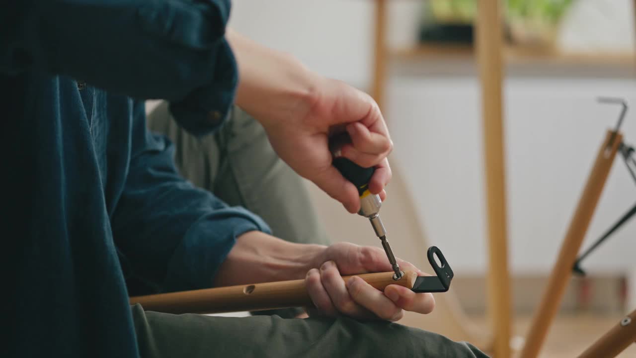 一个年轻的父母自己用螺丝刀拧螺丝慢慢地组装家具视频素材