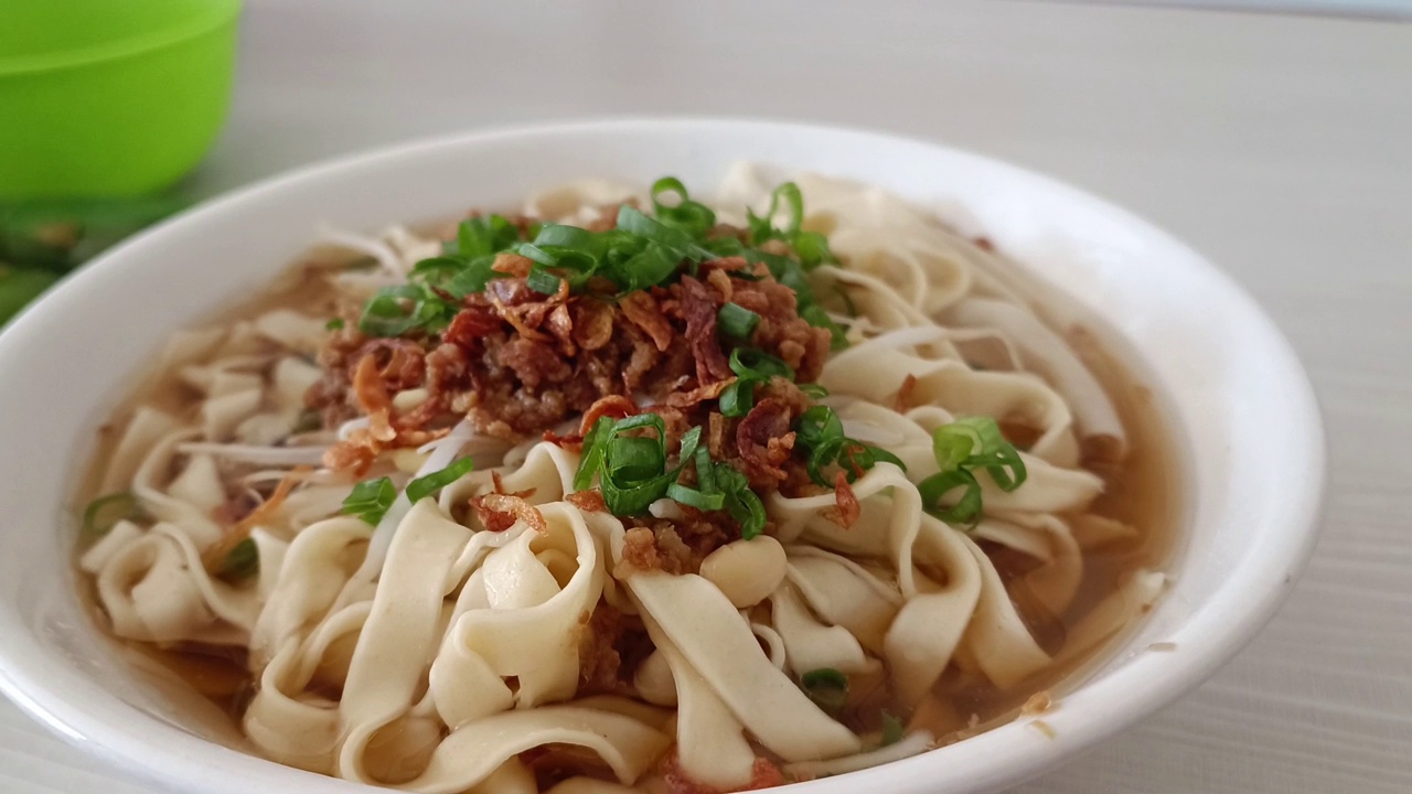 传统的烹饪菜肴:一碗宽面条和猪肉汤里的饺子视频素材