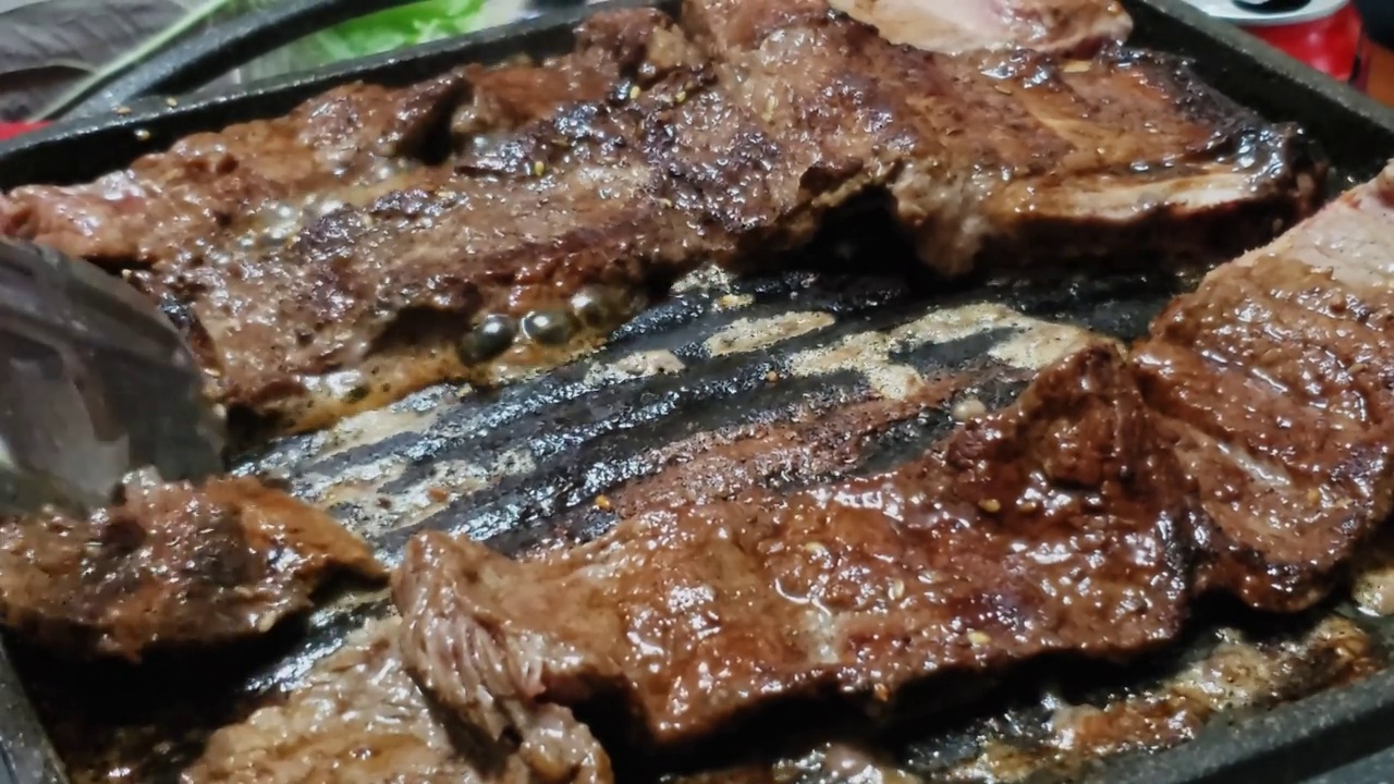 韩式烤牛肉排骨(Kalbi或Galbi)在热盘子上滋滋作响视频素材