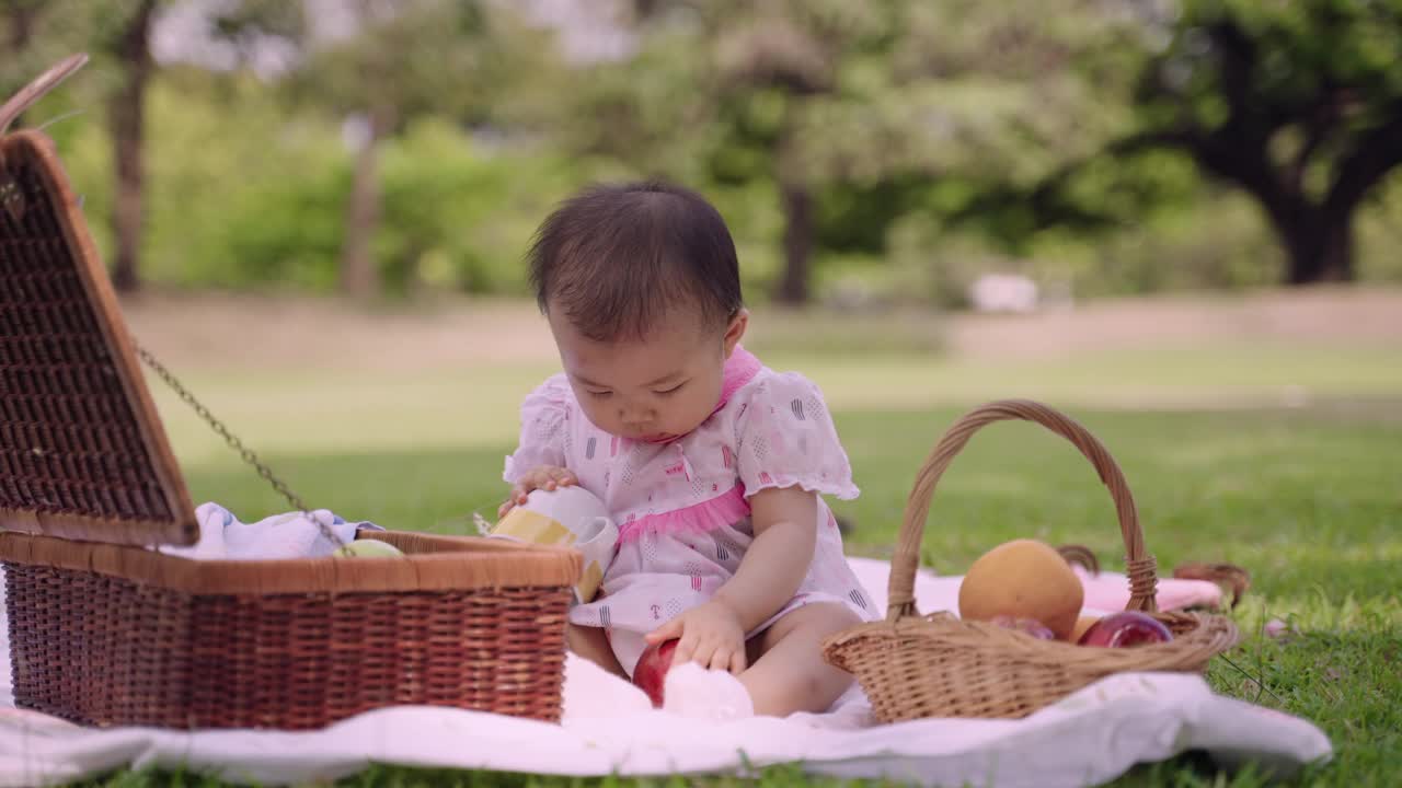 开朗可爱的小女孩拿着杯子独自坐在公园里玩耍。视频下载