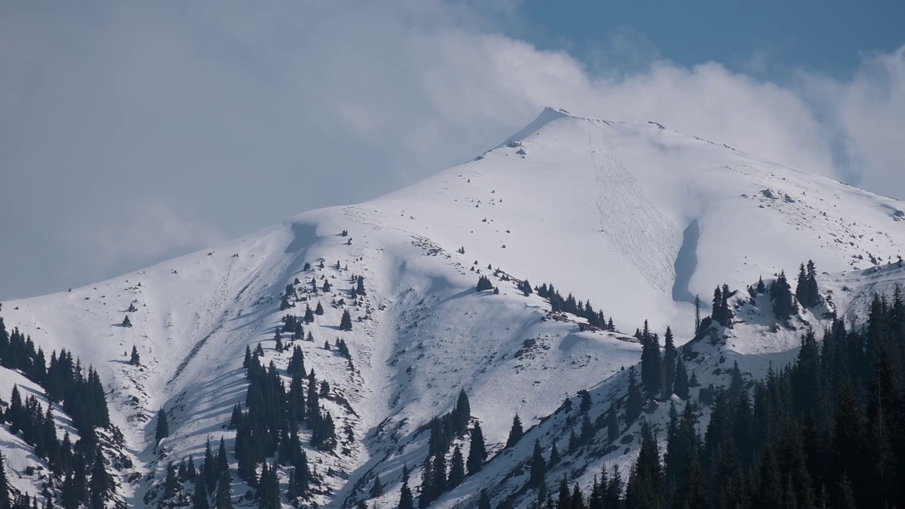 白色的云朵，飘浮在白雪覆盖的山峰上，美丽的山景，哈萨克斯坦阿拉木图的卡蒂尔布拉克峰视频素材