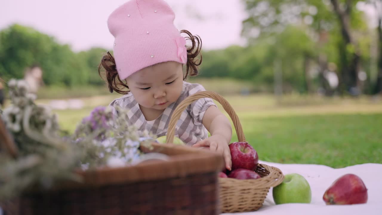 快乐可爱的小女孩坐在公园里拿着苹果，玩着苹果。视频素材