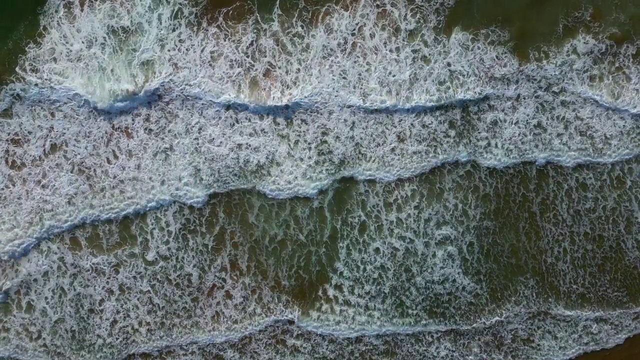 蓝色海浪冲击沙滩的俯视图视频素材