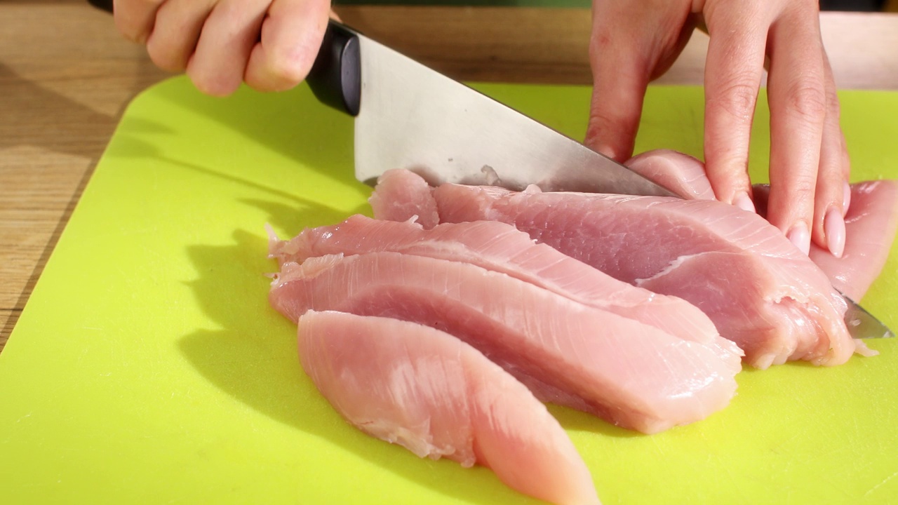 切肉。女性用手用刀切火鸡胸肉片。视频素材
