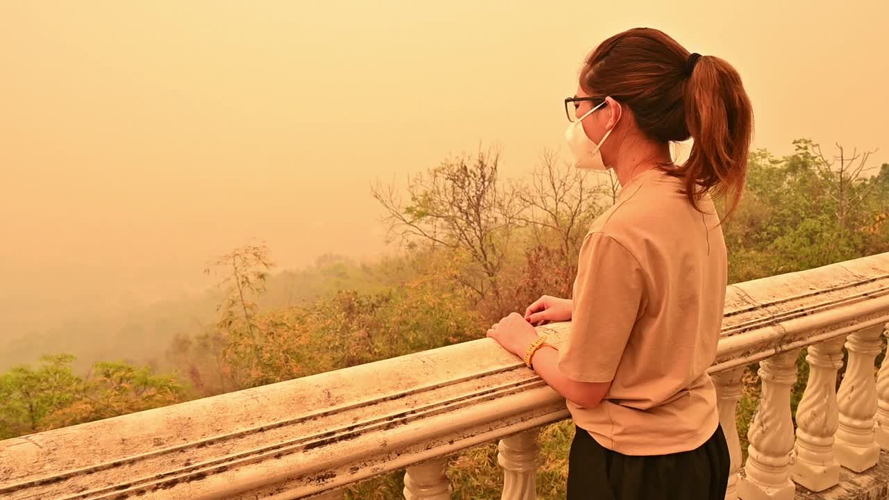 一名忧心忡忡的亚洲妇女戴着n95口罩，以防止严重的空气污染。视频素材