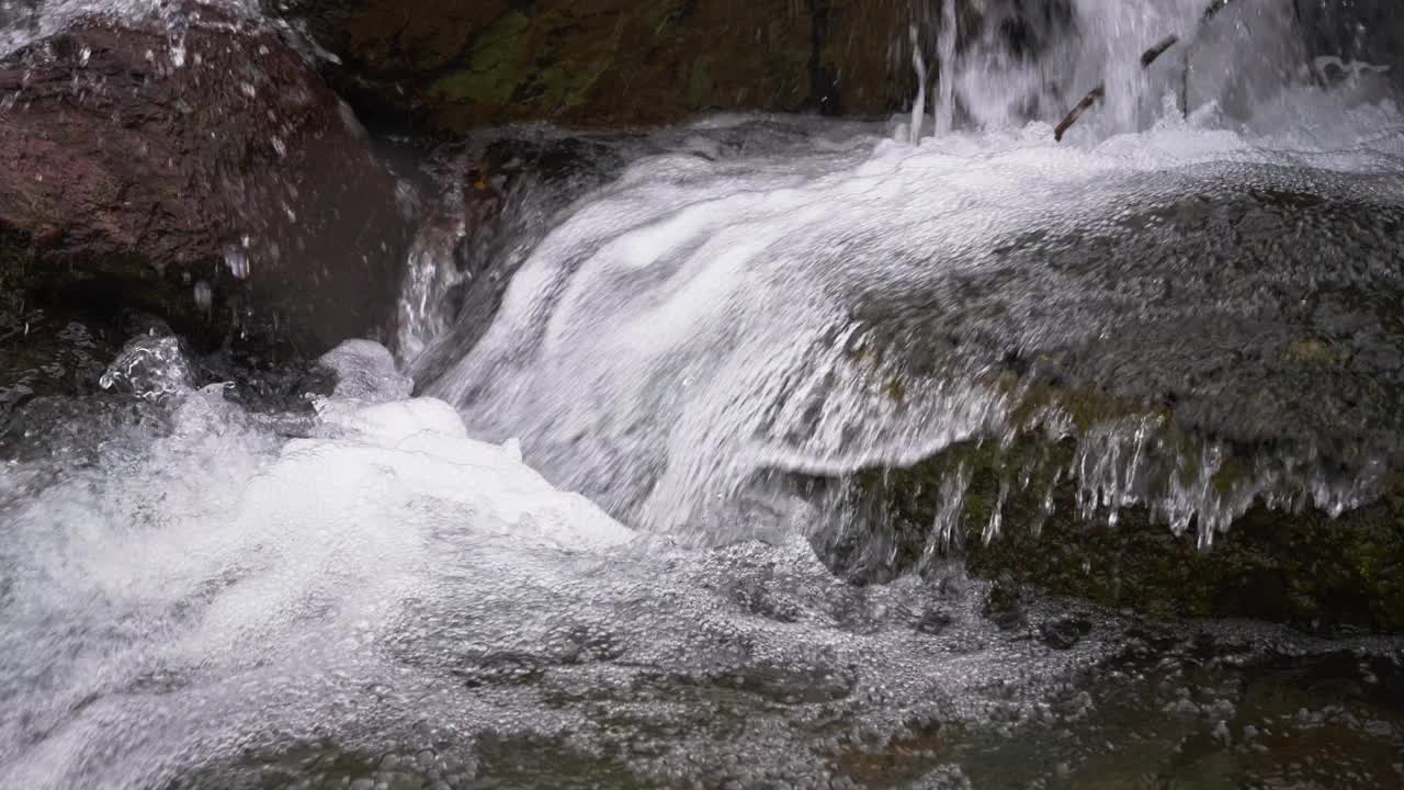 一股山涧的激流穿过石头。山间溪流中的纯水是由于雪的融化而形成的。视频素材