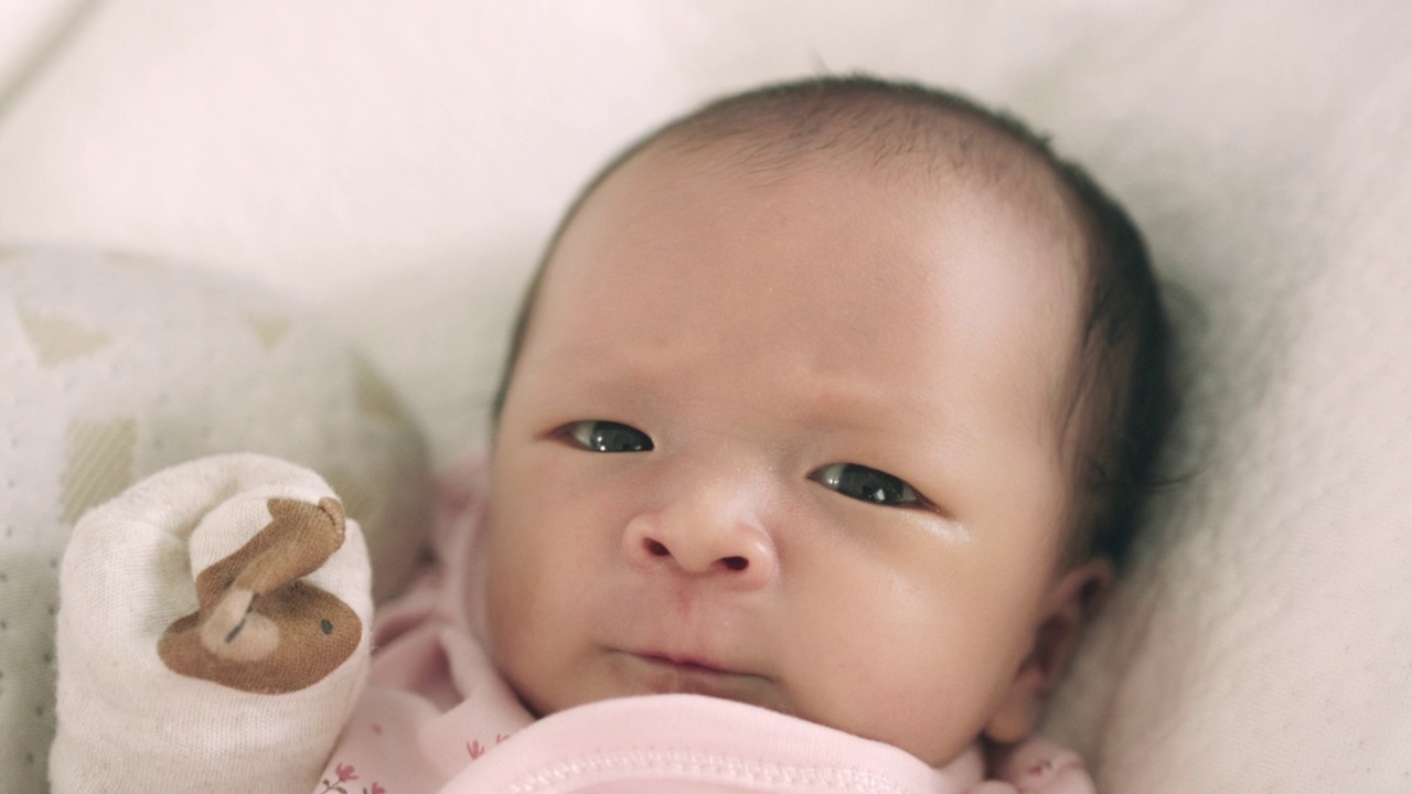 熟睡的亚洲新生婴儿的脸部特写。在妈妈的怀抱里有一个开朗、可爱的心情。视频下载