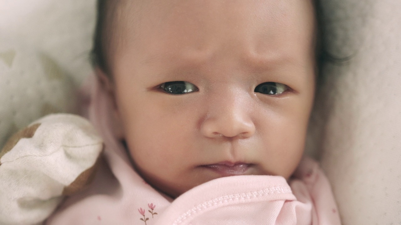 熟睡的亚洲新生婴儿的脸部特写。在妈妈的怀抱里有一个开朗、可爱的心情。视频下载