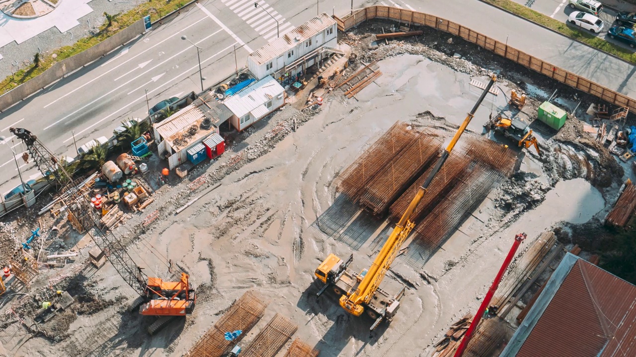 开发多层住宅楼。建筑工地的高清延时鸟瞰图。繁忙的城市交通。施工现场金属结构建筑骨架的加工。有工人在修理各种机器视频素材