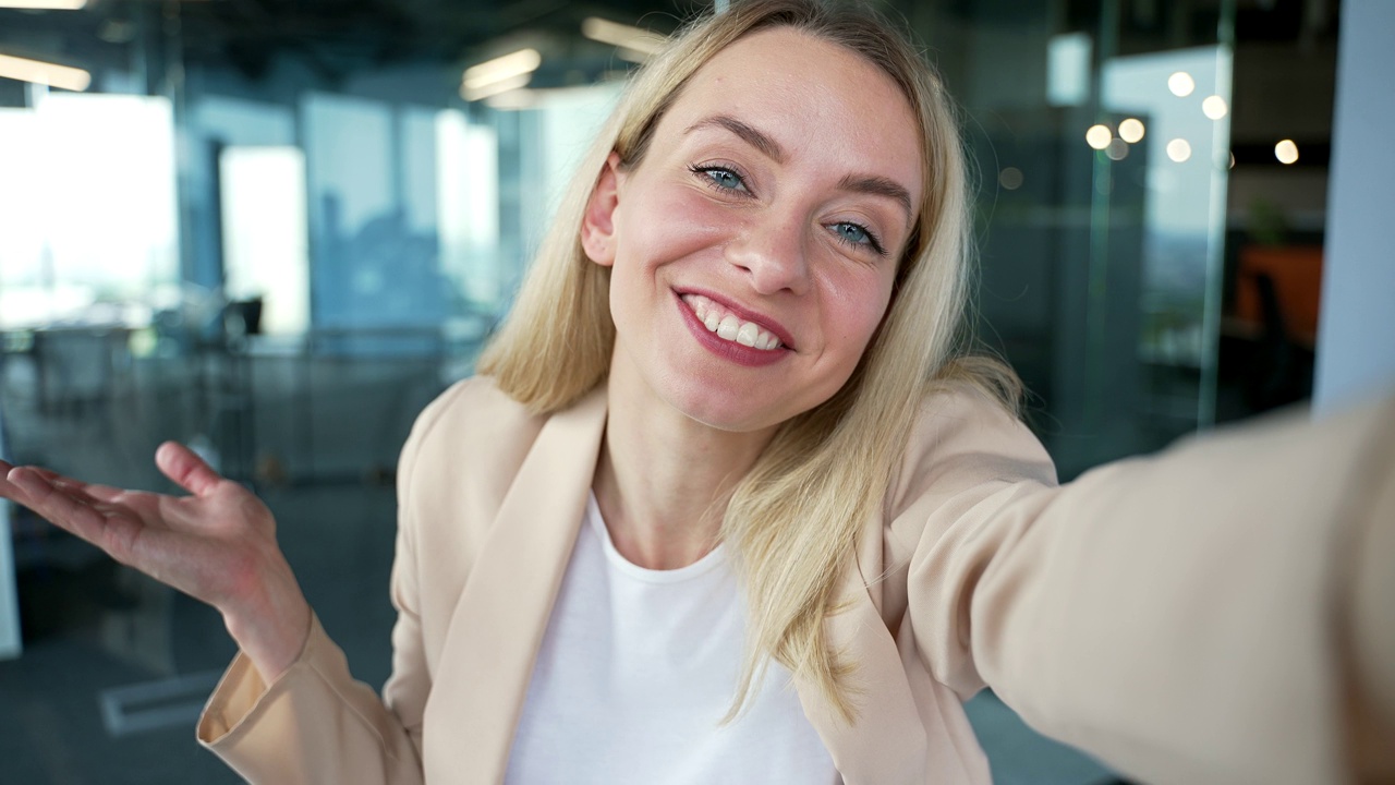 POV网络摄像头视图。一位微笑着的年轻女企业家坐在办公室用智能手机进行视频通话视频素材